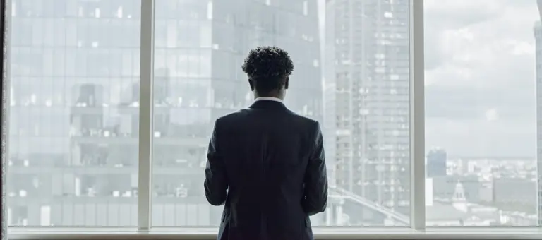 man standing looking out to buildings