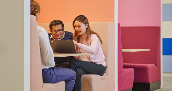 Colleagues sitting around a laptop in a booth