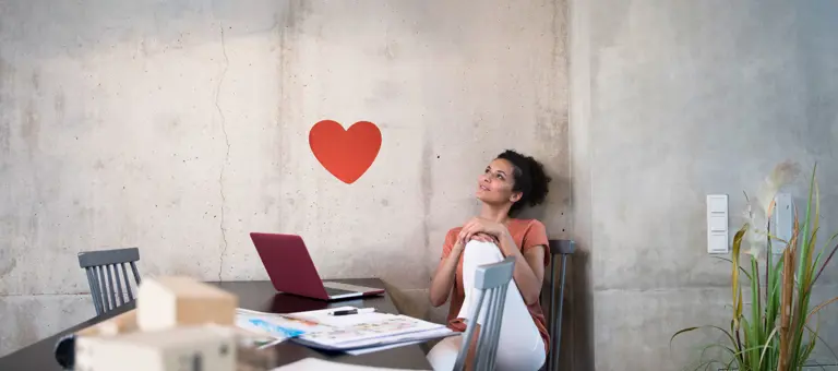 Woman working at a table looking at a heart