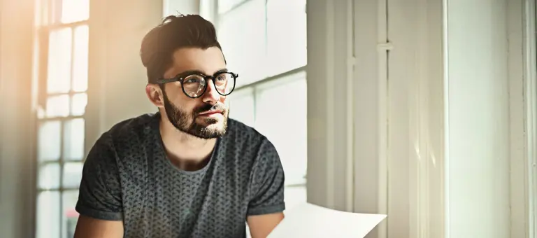 A man working at his desk with pen, paper and tablet