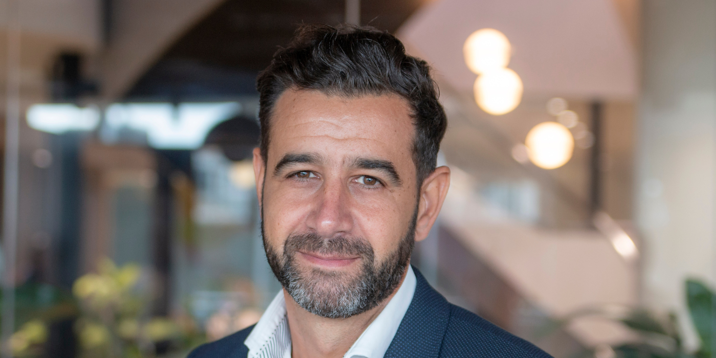 A professional headshot of John Joannou