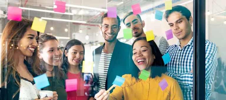 team gathered around window with sticky notes