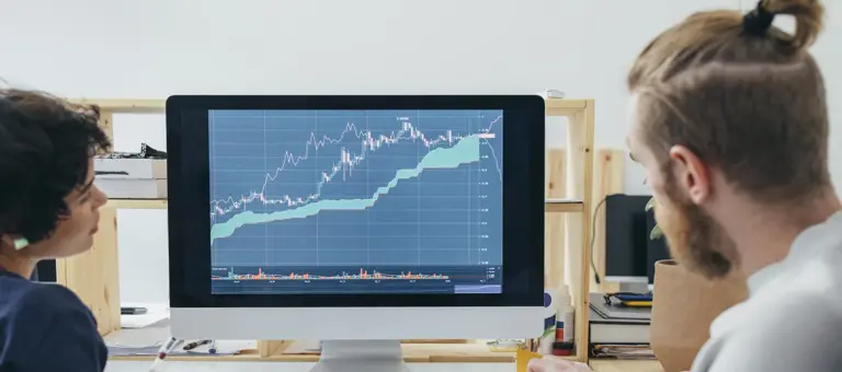 Two people looking at graphs on a computer screen
