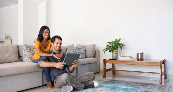 Couple sitting on couch looking at tablet