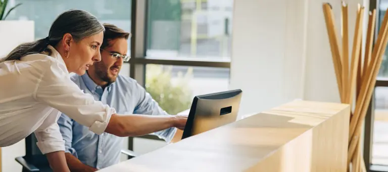 A man and woman in discussion looking at a laptop