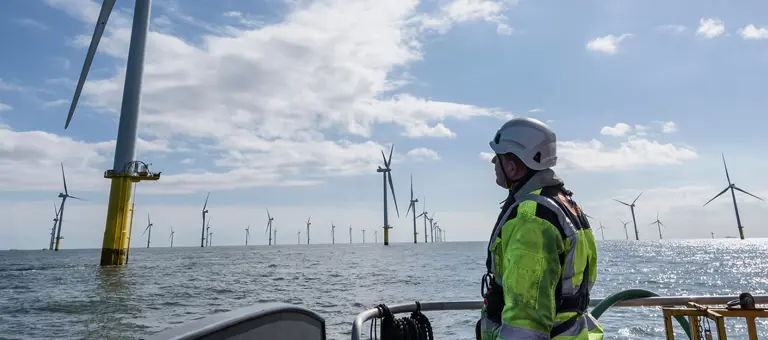 An engineer on a boat looking at an offshore windfarm