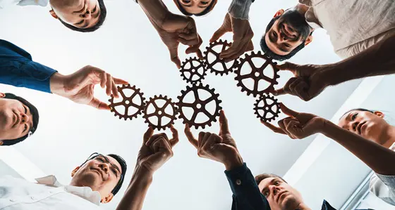 Group of people holding cogs together