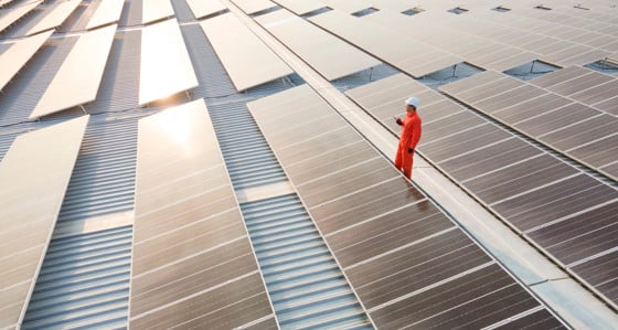An electrician inspects solar panels on a roof