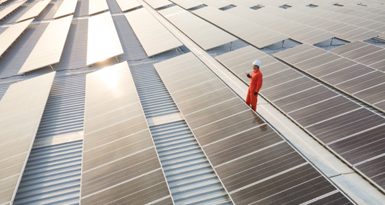 An electrician inspects solar panels on a roof