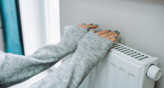 A person warming their hands on a radiator