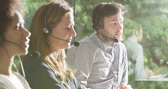 Three colleagues wearing headsets in an office environment