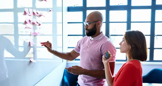 Young woman and male colleague writing ideas on adhesive notes