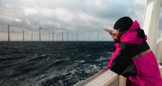 Woman on a boat looking at an offshore wind farm