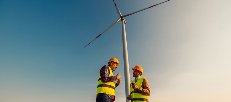 Two engineers in discussion in front of a wind turbine