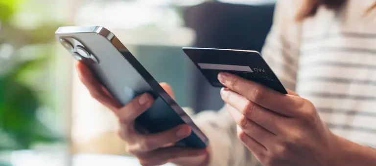 A person using a phone and payment card