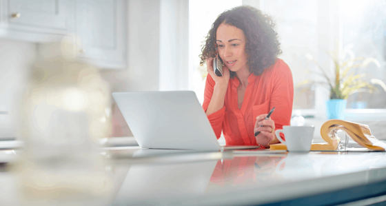 A woman talking on her phone while working on her laptop