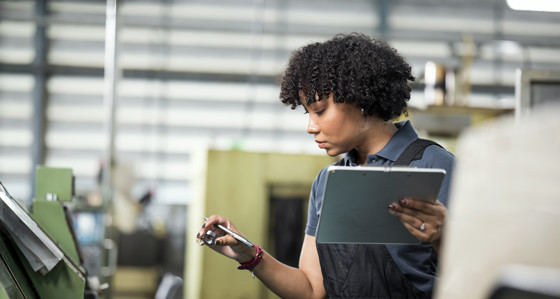 A woman holding a tablet in one hand and a pen and metal ring in the other