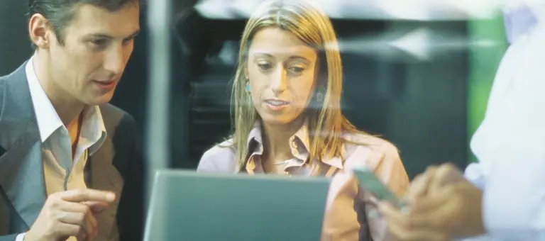 Two colleagues looking at a laptop and discussing what they see