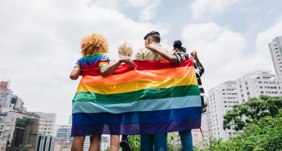 Group of people wrapped in an LGBT flag