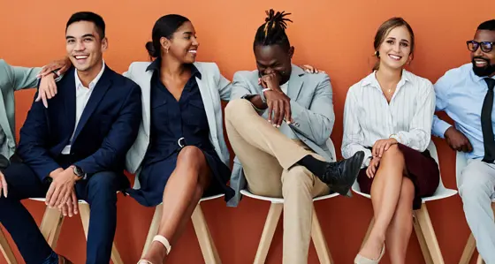 An diverse group of people sitting down smiling and laughing together.