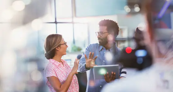 A man with a laptop in discussion with his colleague