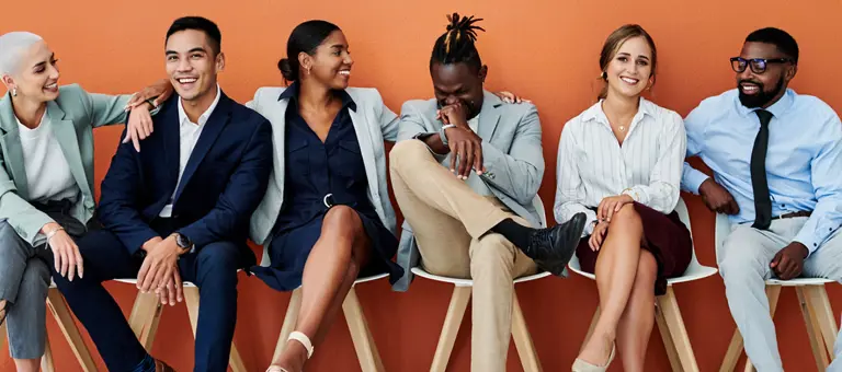 An diverse group of people sitting down smiling and laughing together.