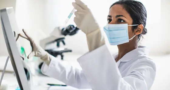A lab technician looking at a sample in a test tube