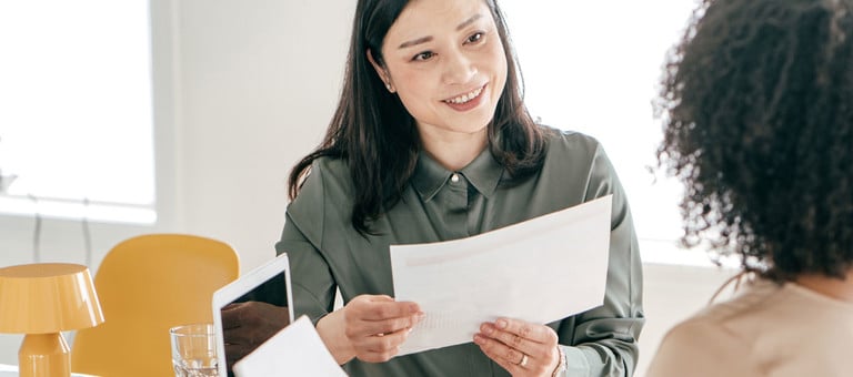 A women smiling and holding a report