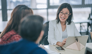 A woman smiling at her colleagues while working on a laptop