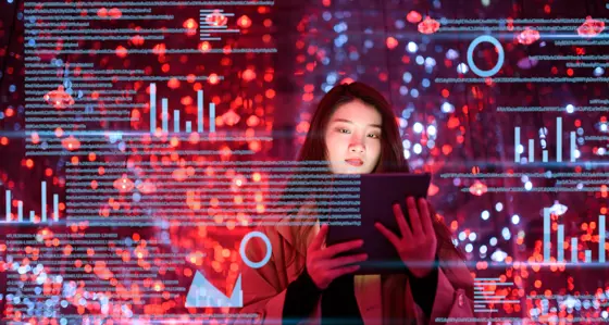 Woman using tablet with virtual screen of graphs and data surrounding her