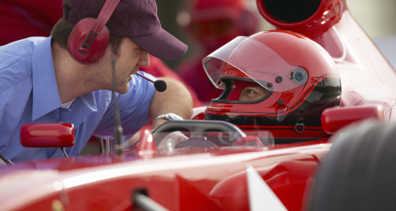 Racing driver talking with a man wearing a headset during a pit stop