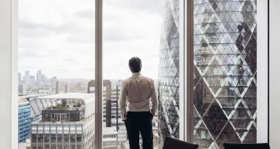 Businessman looking out window at London's financial district