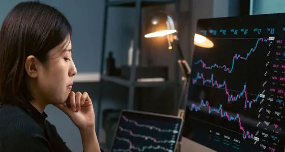 A woman looking at graphs on multiple screens