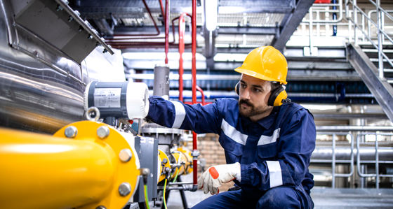 Refinery blue collar worker standing by LPG pipeline