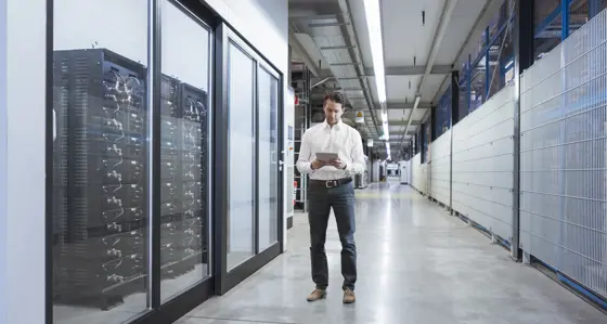 Man on tablet next to a server room