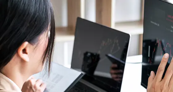 A woman touching a screen displaying stocks index prices