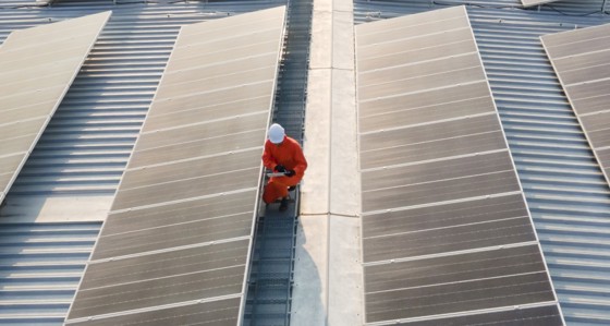 An engineer inspecting solar panels on a roof