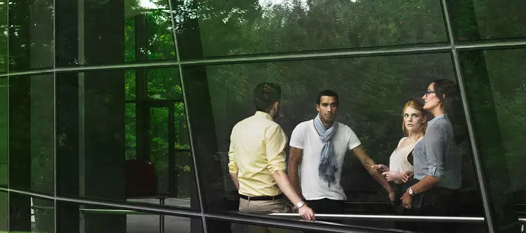 A group of people can be seen through a window with reflections of plants around them
