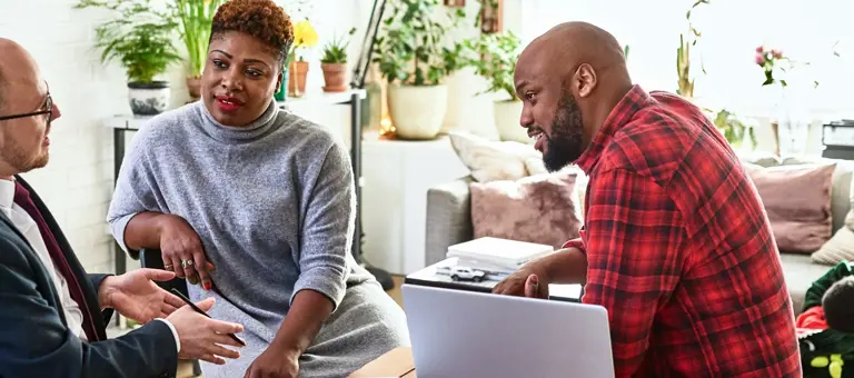 A couple in their home in discussion with a business advisor