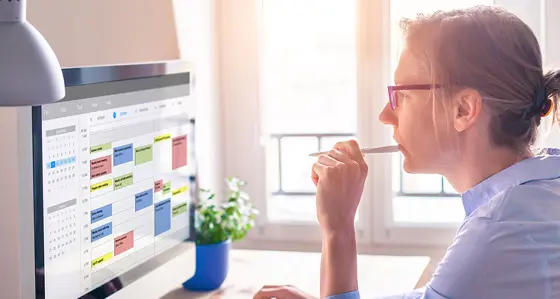 A thoughtful woman staring at the digital calendar on her computer screen