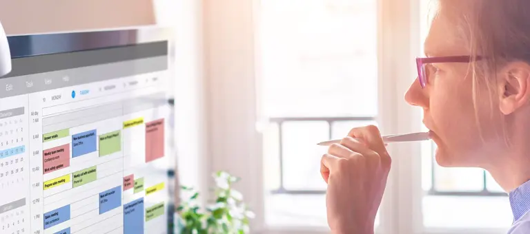 A thoughtful woman staring at the digital calendar on her computer screen