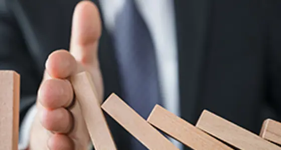 A hand preventing the domino effect of blocks falling over