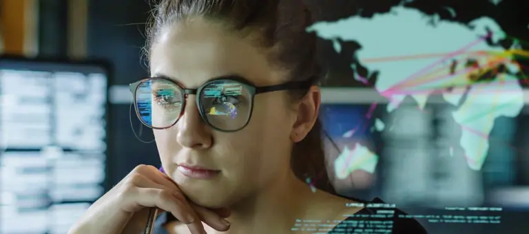 A woman looking thoughtful in front of multiple computer screens