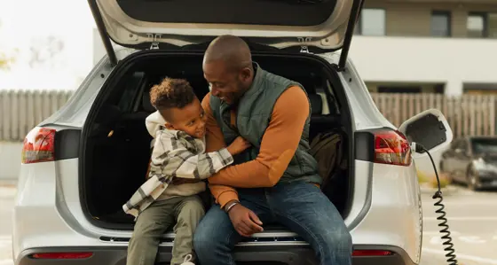 A father and his son playing together while their electric car is charging