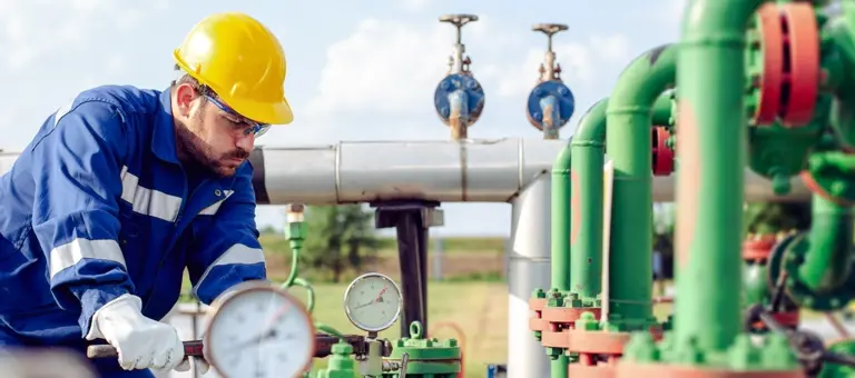 An engineer with a large wrench tightening up a pressure gauge fitting