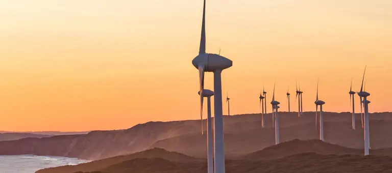 A windfarm in hills front of orange skies