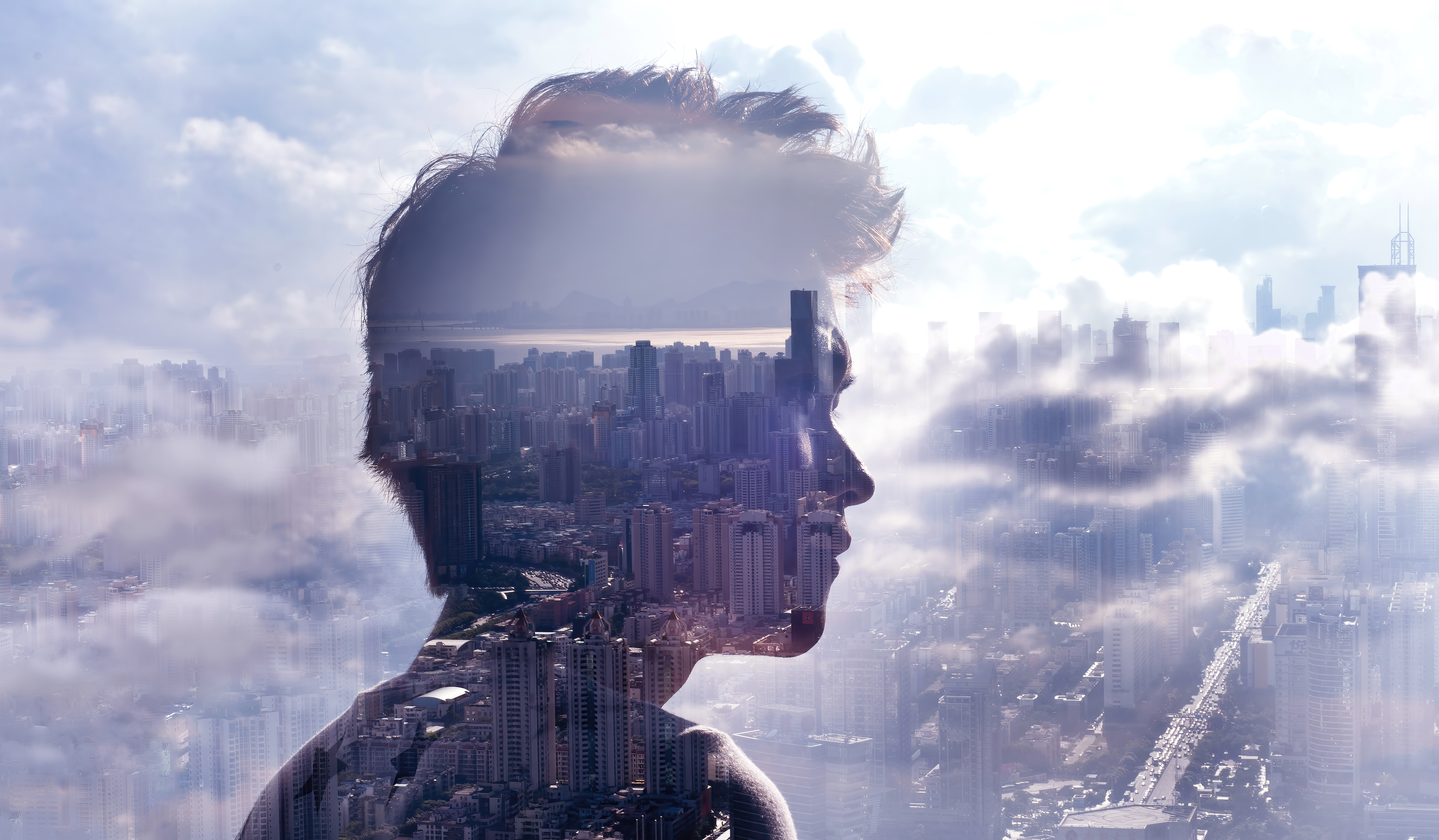 Man's head superimposed over a cityscape in clouds