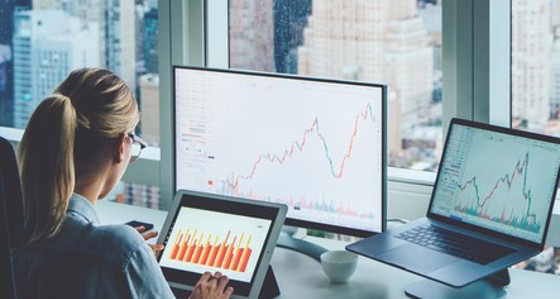 A woman looking at graphical data on multiple screens