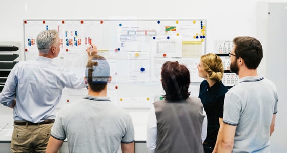 A man writing on data sheets pinned on a whiteboard