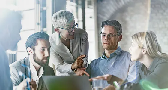 Team of business colleagues talking while working on computer in the office
